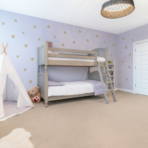 Cozy kids room with purple walls decorated with golden star wall decals, bunk bed, play tent, and soft carpet