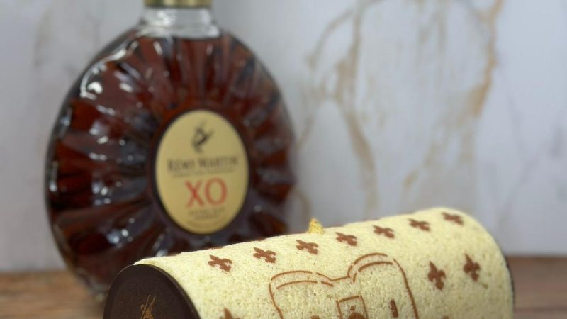 Cake decorated with custom Cognac stencil design next to Rémy Martin XO bottle