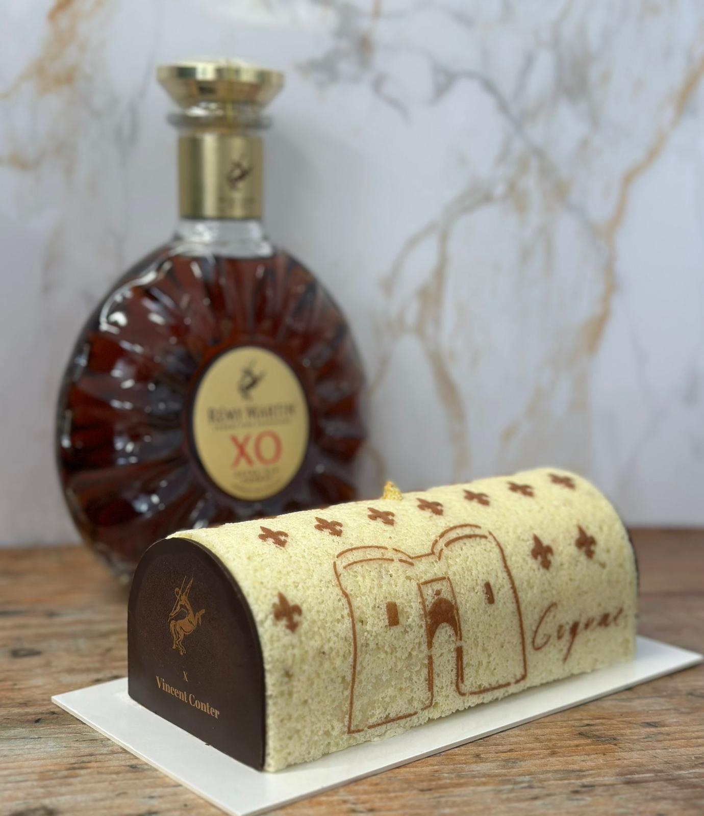 Cake decorated with custom Cognac stencil design next to Rémy Martin XO bottle
